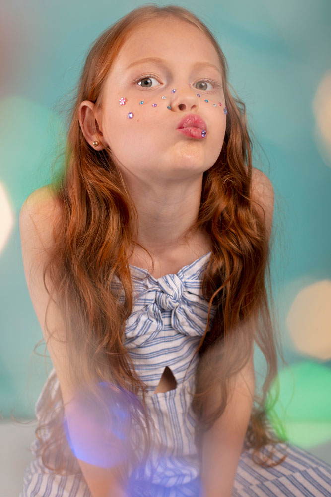 Niña con gemas en la cara, brillantes gemas en el rostro, retrato de una niña.